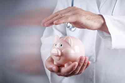 Arzt hält Hand über Sparschwein - © andranik123 - stock.adobe.com