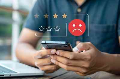 Mann bedient Smartphone, darüber negatives Smiley und schlechte Sterne Bewertung - © main_asn - stock.adobe.com